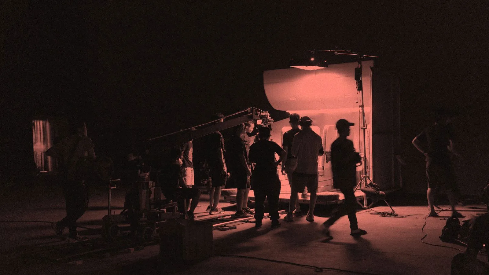 A film crew working around a camera and lighting rig on a night shoot