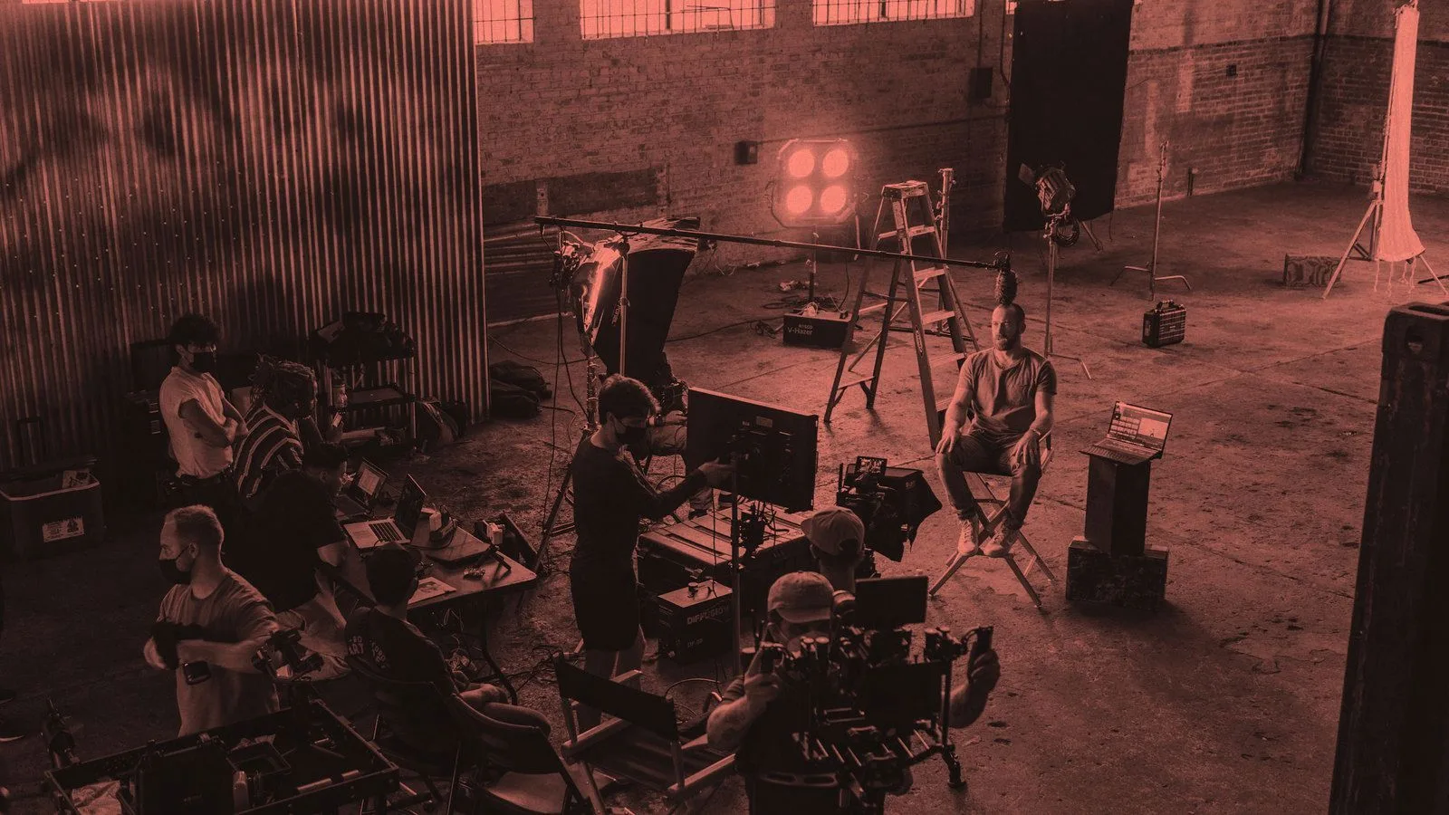 A film crew and lighting setup on a warehouse location